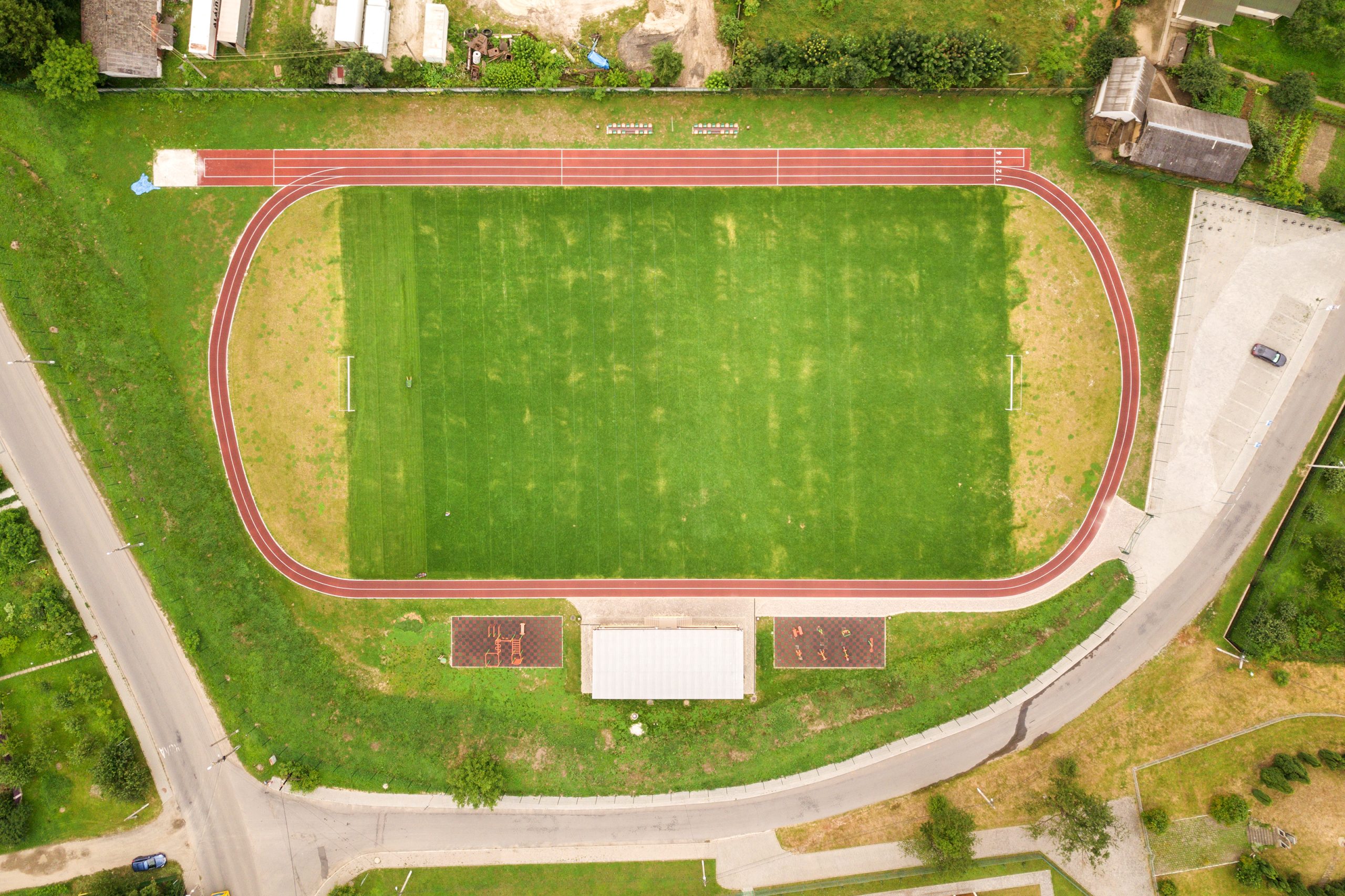 Aerial view of sports stadium with red running tracks and green grass football field.